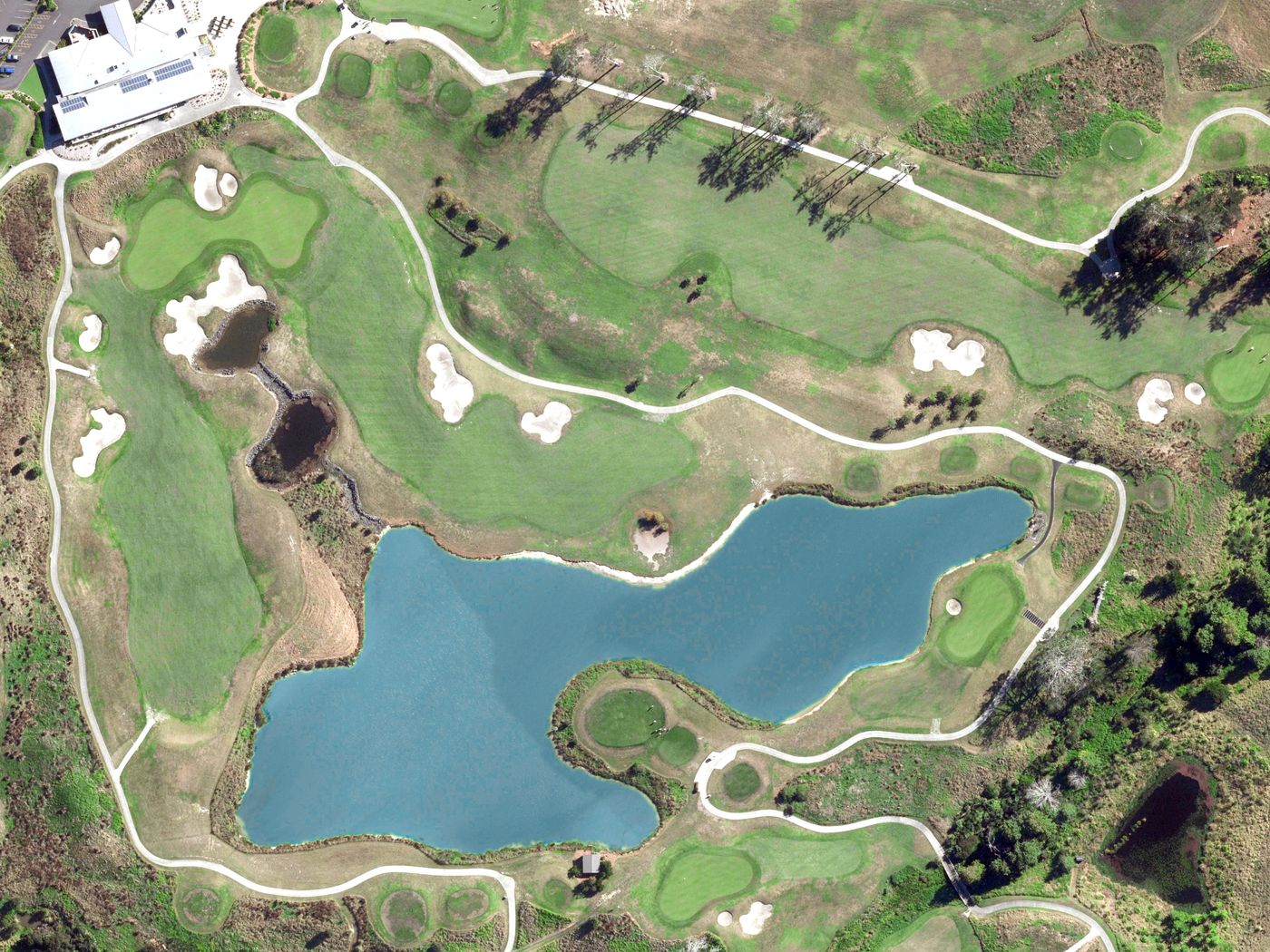 Aerial of Wainui golf course with clubhouse, lake and bunkered holes